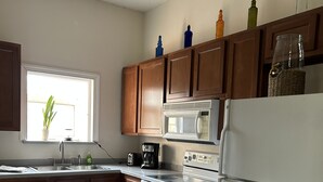 Une cuisine avec des meubles de rangement en bois, un réfrigérateur blanc, une cuisinière et un four à micro-ondes.
