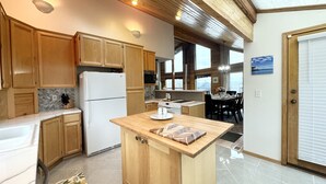 Une cuisine avec des meubles en bois, un réfrigérateur blanc, un îlot central et un coin repas comprenant une table et des chaises.