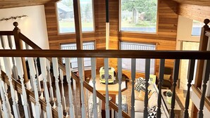 Un intérieur en bois avec un escalier, de grandes fenêtres et une vue sur l’extérieur.