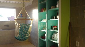 Een badkamer met een hangstoel, een badkuip en planken met toiletartikelen.