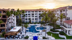 A resort with a central pool, multiple balconies, and palm trees. - Semana Santa Mazatlán 2024, del 24 al 31 de Marzo 2024 (Mazatlán)