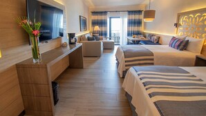 A modern hotel room with a flat-screen TV, a dining area, a sofa, and a bed with striped bedding. - Semana Santa Mazatlán 2024, del 24 al 31 de Marzo 2024 (Mazatlán)
