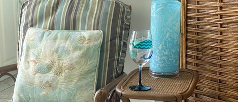 A wicker chair with a striped cushion and a glass vase with a blue pattern.