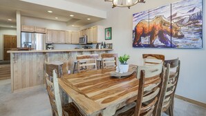 A spacious kitchen with wooden cabinets, a central island, and a dining area with rustic chairs. - Walk to Ski Lift: Breck Condo w/ Hot Tub (Breckenridge)