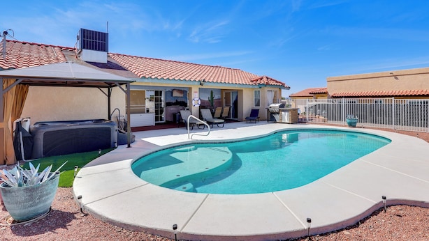 A backyard with a swimming pool, a hot tub, and a covered patio area with lounge chairs. - Cozy Lake Havasu City Home - Pool and Hot Tub (Lake Havasu City)