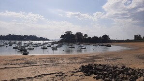 Une plage avec des bateaux, un rivage sablonneux et un bâtiment en arrière-plan.