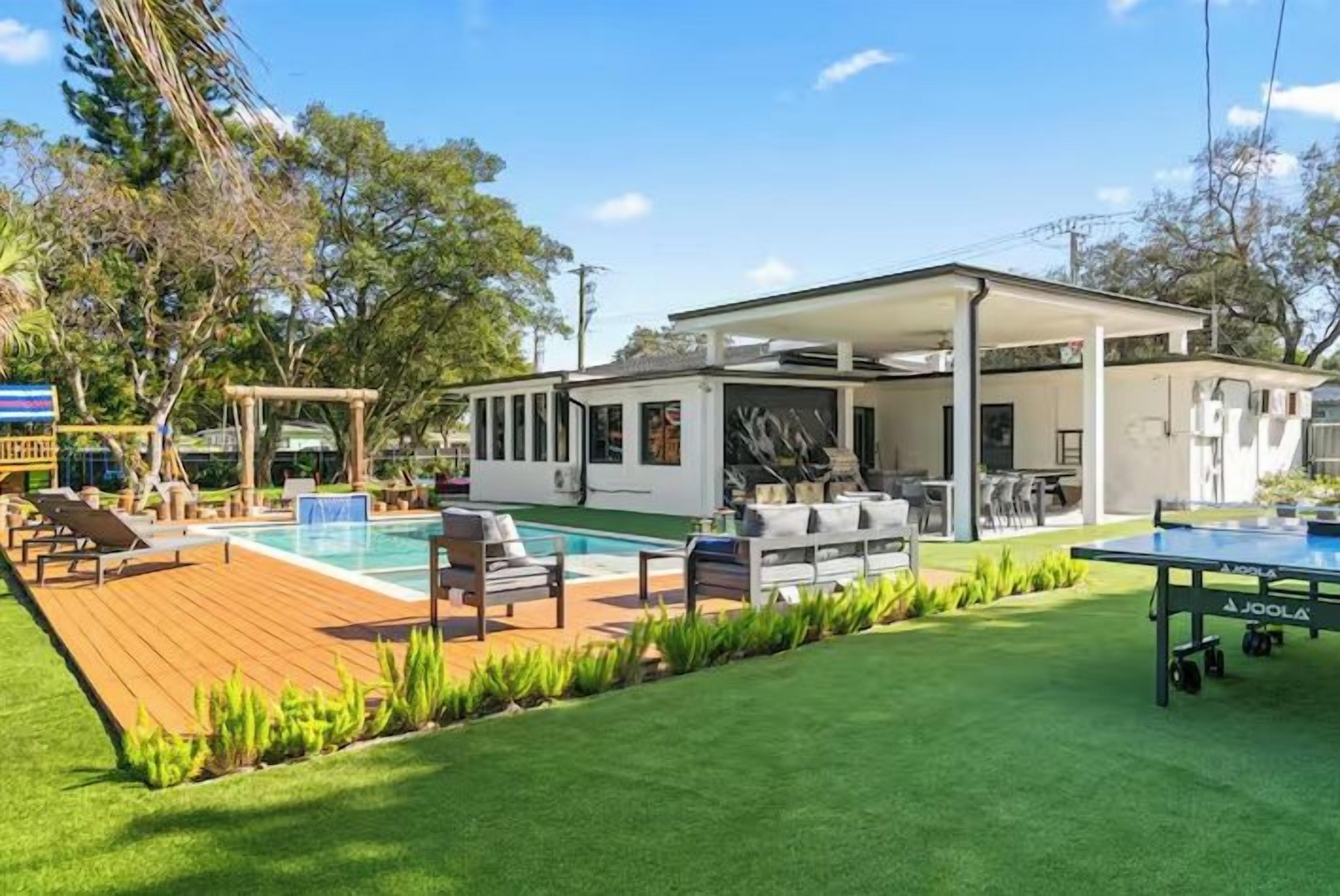 A modern house with a pool, outdoor seating, and a ping pong table.