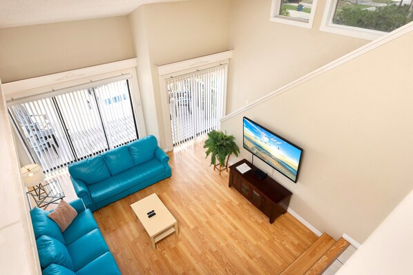 Una sala de estar con un sofá azul, una mesa de centro y un televisor sobre un mueble de madera.