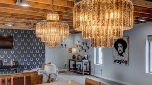 A dining area with a large table and benches, wooden ceiling beams, and decorative chandeliers.