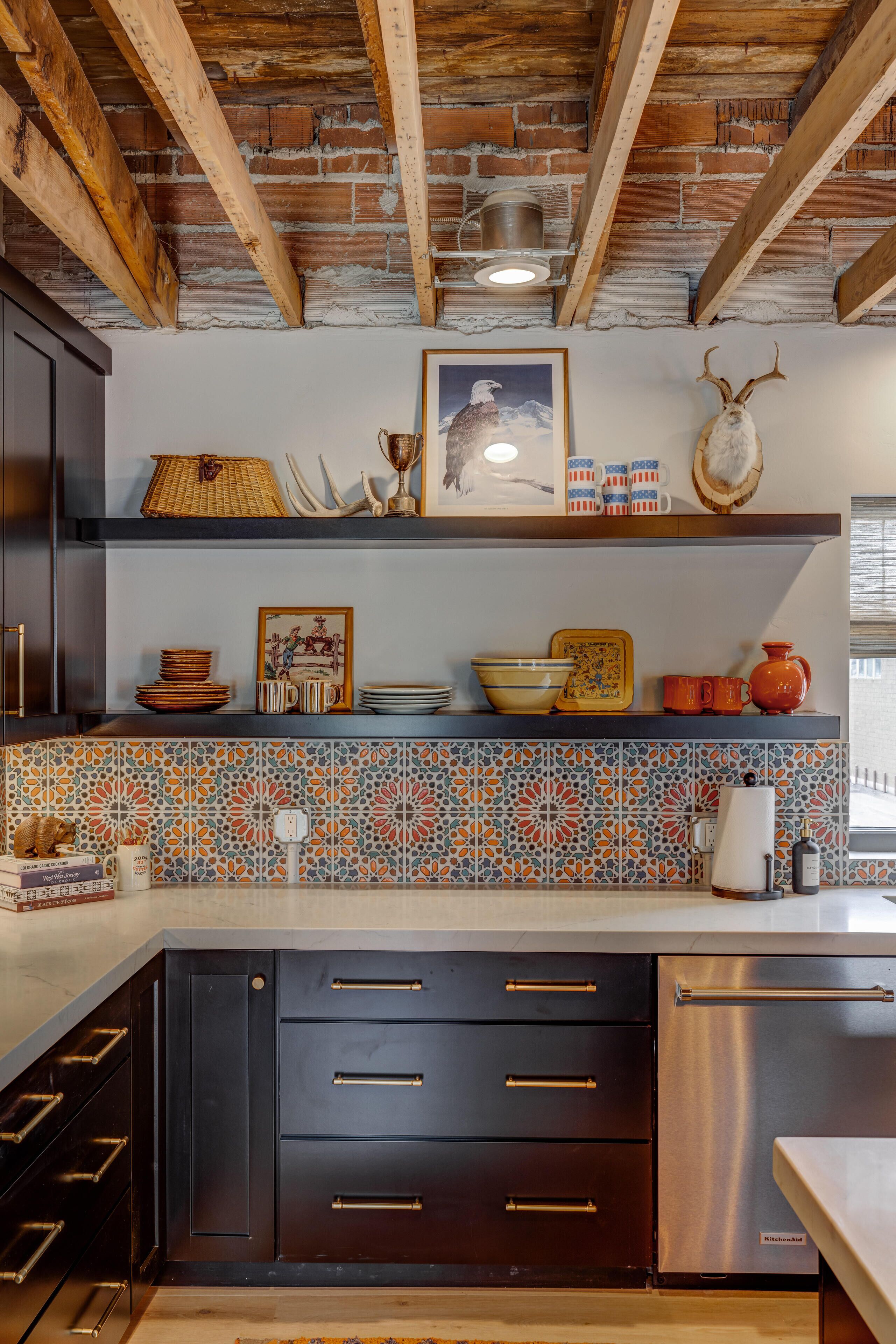 Een keuken met zichtbare houten balken, een betegelde spatwand en moderne apparatuur.