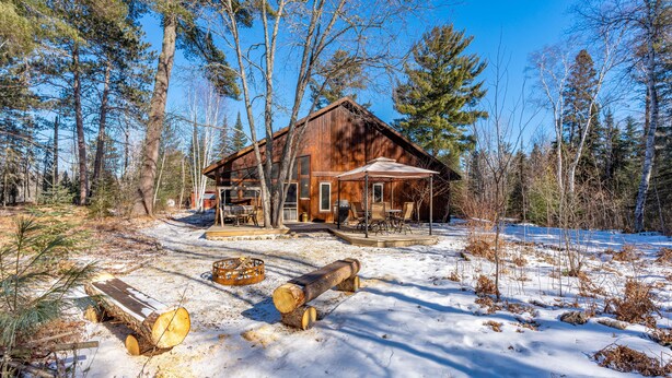 A rustic cabin with a porch, surrounded by snow and trees. - Wooded setting, close to town, clean! ATV & snowmobile from front door! (Ely)