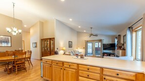A spacious kitchen with wooden cabinets, a large island, and a dining area with a wooden table and chairs. - Wooded setting, close to town, clean! ATV & snowmobile from front door! (Ely)