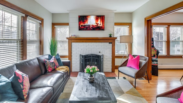 A living room with a fireplace, a sofa, a coffee table, and a TV mounted above the fireplace.
