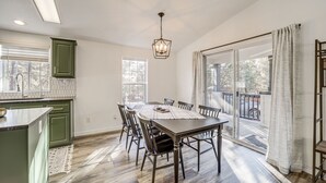 A dining area with a table, chairs, and a pendant light. There is a window with a view of the outdoors. - Mtn Views + Playground: Family-Friendly Pine Cabin (Pine)