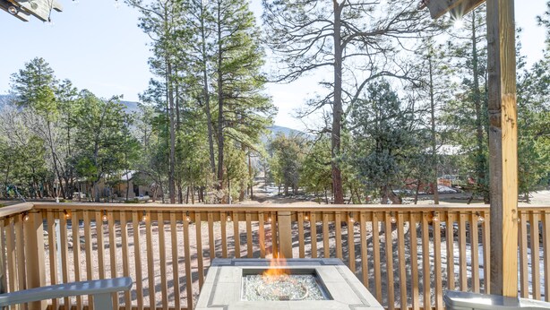 A deck with a fire pit, wooden railings, and a view of trees and mountains. - Mtn Views + Playground: Family-Friendly Pine Cabin (Pine)