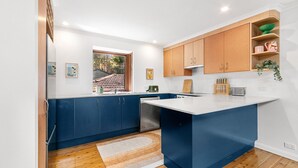 Eine moderne Küche mit blauen Schränken, einer weißen Arbeitsplatte und Holzregalen.