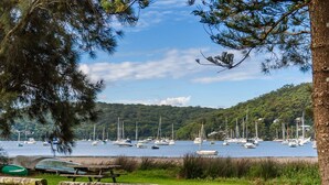 A lakeside view with boats, a picnic table, and a forested hill in the background.