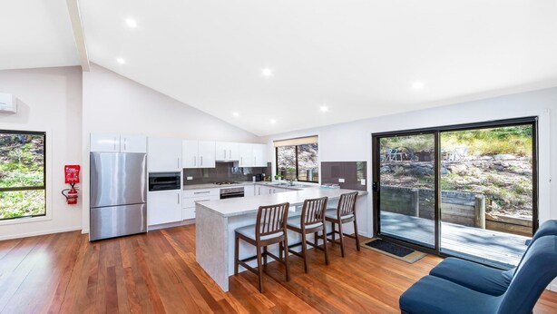 A modern kitchen with white cabinets, a stainless steel refrigerator, and a large island with bar stools.
