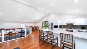A modern kitchen with white cabinets, a stainless steel refrigerator, and a dining area with wooden chairs and a table.
