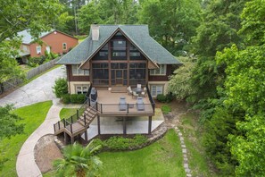 A large house with a covered patio, a deck, and a staircase leading to the entrance.