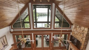 Ein geräumiger Loft-Raum mit hoher Decke, großen Fenstern mit Seeblick und einem Steinkamin.