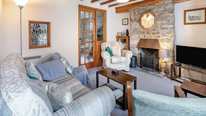 Een gezellige woonkamer met een bank, fauteuil en een open haard.