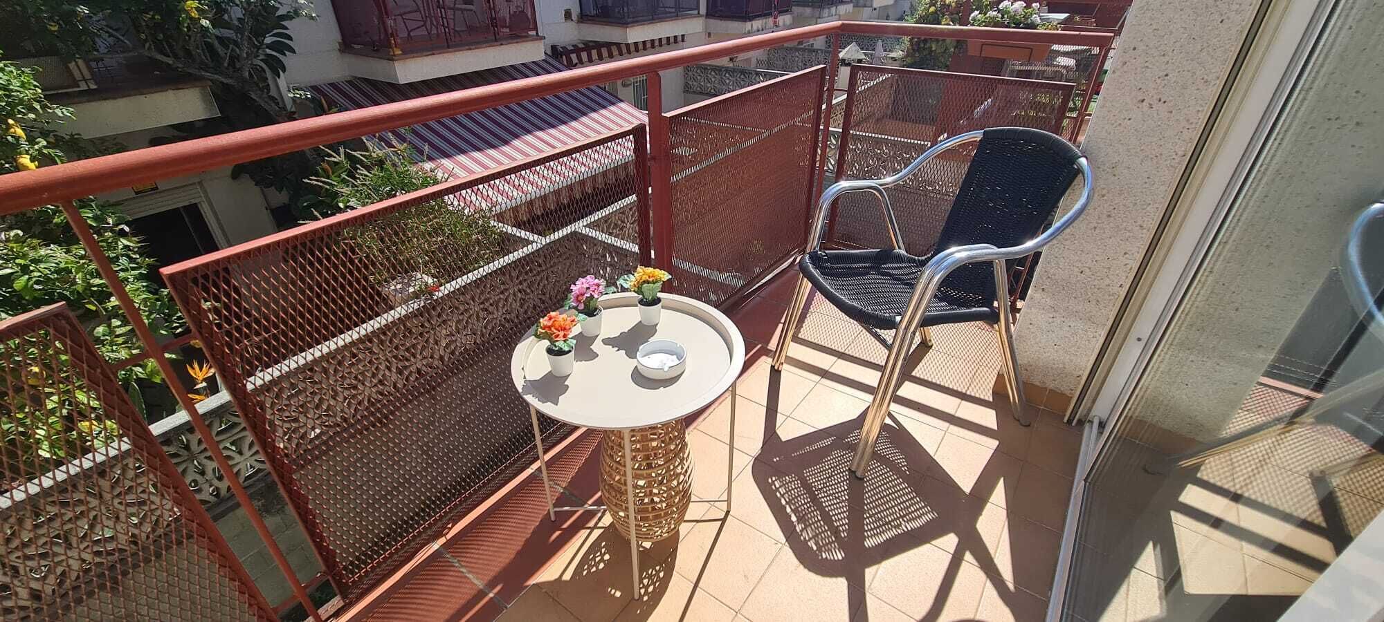 Un balcon avec une table et des chaises, une balustrade décorative et une vue sur les bâtiments.
