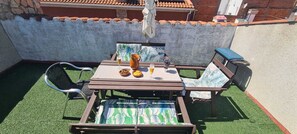 Une terrasse avec une table, des chaises et une petite plante en pot.