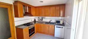 Une cuisine avec des meubles en bois, une cuisinière à gaz, un four à micro-ondes et un lave-vaisselle.