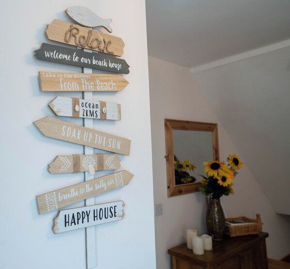 Uma parede com placas de madeira com frases como 'Relaxe' e 'Casa Feliz'.