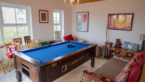 Une table de billard dans une pièce avec un plafond en bois, un canapé et une fenêtre.