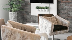 A modern living room with a stone wall, a flat-screen TV, a sofa, and a coffee table. - Nazaré Rooftop Oásis (Nazaré)