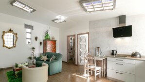 A compact living space with a sofa, a chair, a dining table, and a kitchenette. - Casas da Gralha - Alecrim (Alcobaça)