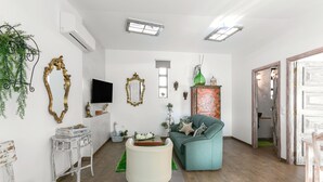 A living room with a sofa, a coffee table, and a TV. There are decorative mirrors and a plant on the wall. - Casas da Gralha - Alecrim (Alcobaça)