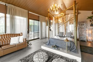 A modern bedroom with a large bed, a leather sofa, and a chandelier. - Casas da Gralha - Corvo (Alcobaça)
