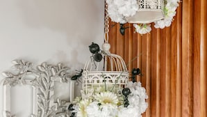 Een houten wand met twee witte vogelkooien, elk versierd met witte bloemen en zwarte decoratieve elementen.