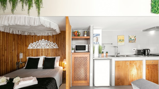 Een kleine hotelkamer met een bed, een kitchenette en een badkamer.