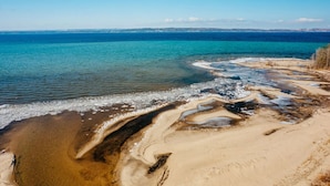 Et kystlandskab med en sandstrand og klart, blåt vand.