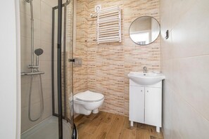 Een douche, handdoeken, zeep, toiletpapier