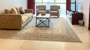A spacious living room with a sofa, two armchairs, a coffee table, and a TV stand.