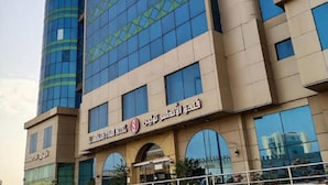 A modern hotel with a glass facade and a prominent sign in Arabic.