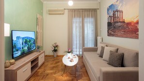 Sala de estar com televisão, sofá e pintura de ruínas antigas.