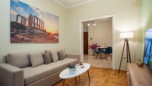 Uma sala de estar com sofá, mesa de centro e pintura de ruínas antigas.