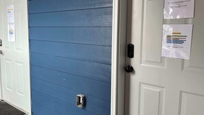 Una porta blava amb una clau electrònica i un timbre. Hi ha dos avisos a la porta: un sobre l'horari de la sala de bugaderia i un altre sobre la sala de préstecs.