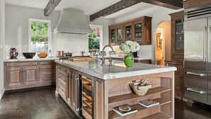 Una cocina moderna con armarios de madera, una isla grande y un refrigerador de acero inoxidable.