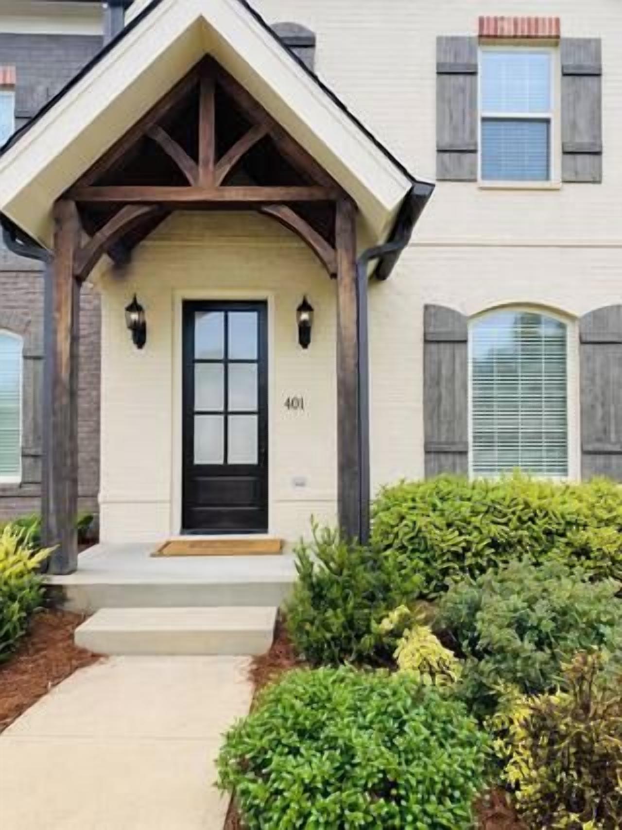 A house with a front porch, a black door, and a number 406 on the door.