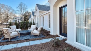 Een modern huis met een patio, voorzien van buitenmeubilair en een vuurkorf.