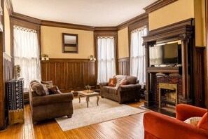 Un salon traditionnel avec une cheminée, deux canapés, une table basse et un téléviseur.