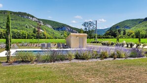 Un espace piscine avec des chaises longues, un petit abri de jardin et un jardin agrémenté de lavande.