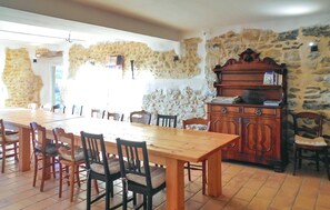 A dining area with a large wooden table and chairs, stone walls, and a wooden cabinet with books. - Gorgeous home in St Sauveur de Cruzière (St Sauveur de Cruzière)